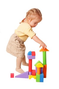 Baby girl building from toy blocks. Isolated on white background